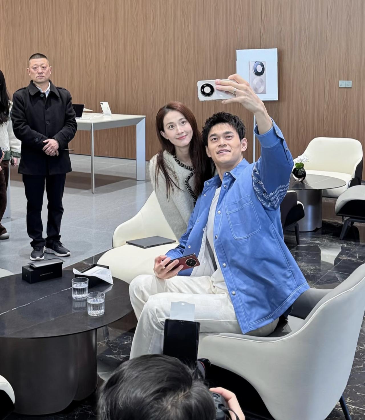 奥运冠军孙杨和妻子张豆豆一起到线下店铺买国产手机，夫妻俩坐在椅子上，一起试玩各型