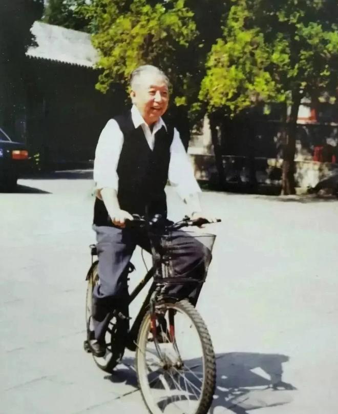 华国锋退休之后在院子里骑自行车。他的头发梳理的一丝不苟，精神状态看起来很好，退