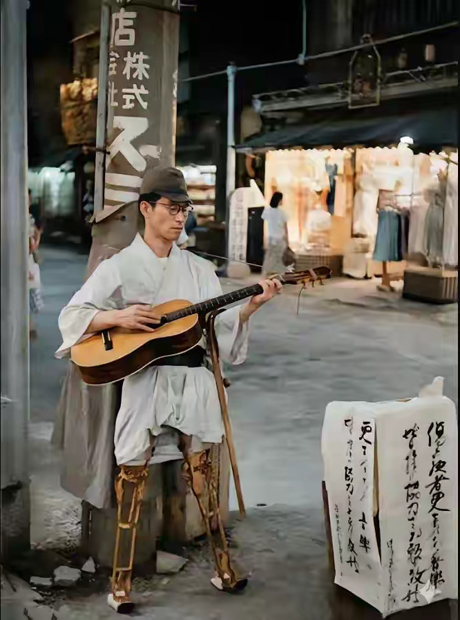 1951年，东京浅草区，装义肢的鬼子残兵在街头弹吉他乞讨。二战结束，数万被遣返的