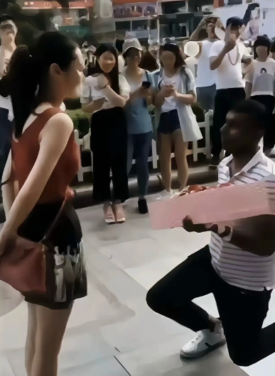 中国女孩就该这样！又一外国男子向中国女孩求爱了，男子手拿鲜花，当街单膝下跪深