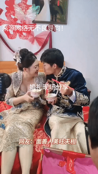 农村婚礼现场。新郎新娘正坐在床上按照婚礼习俗，互相喂对方饺子吃。看起来新娘子