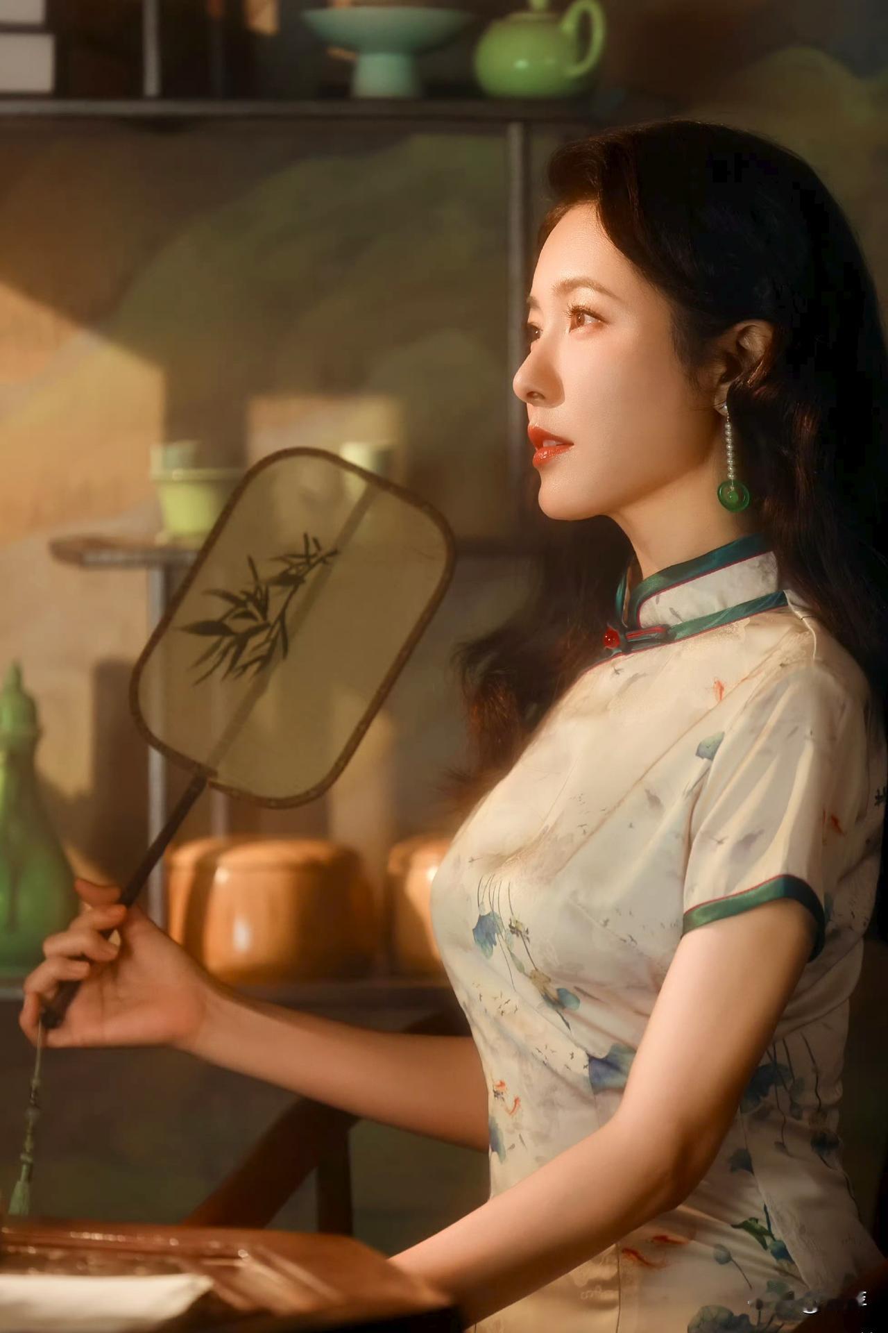 曾黎身着素雅印花旗袍，手持绘竹团扇，身姿曼妙，在古朴陈设映衬下，尽显温婉娴静的古