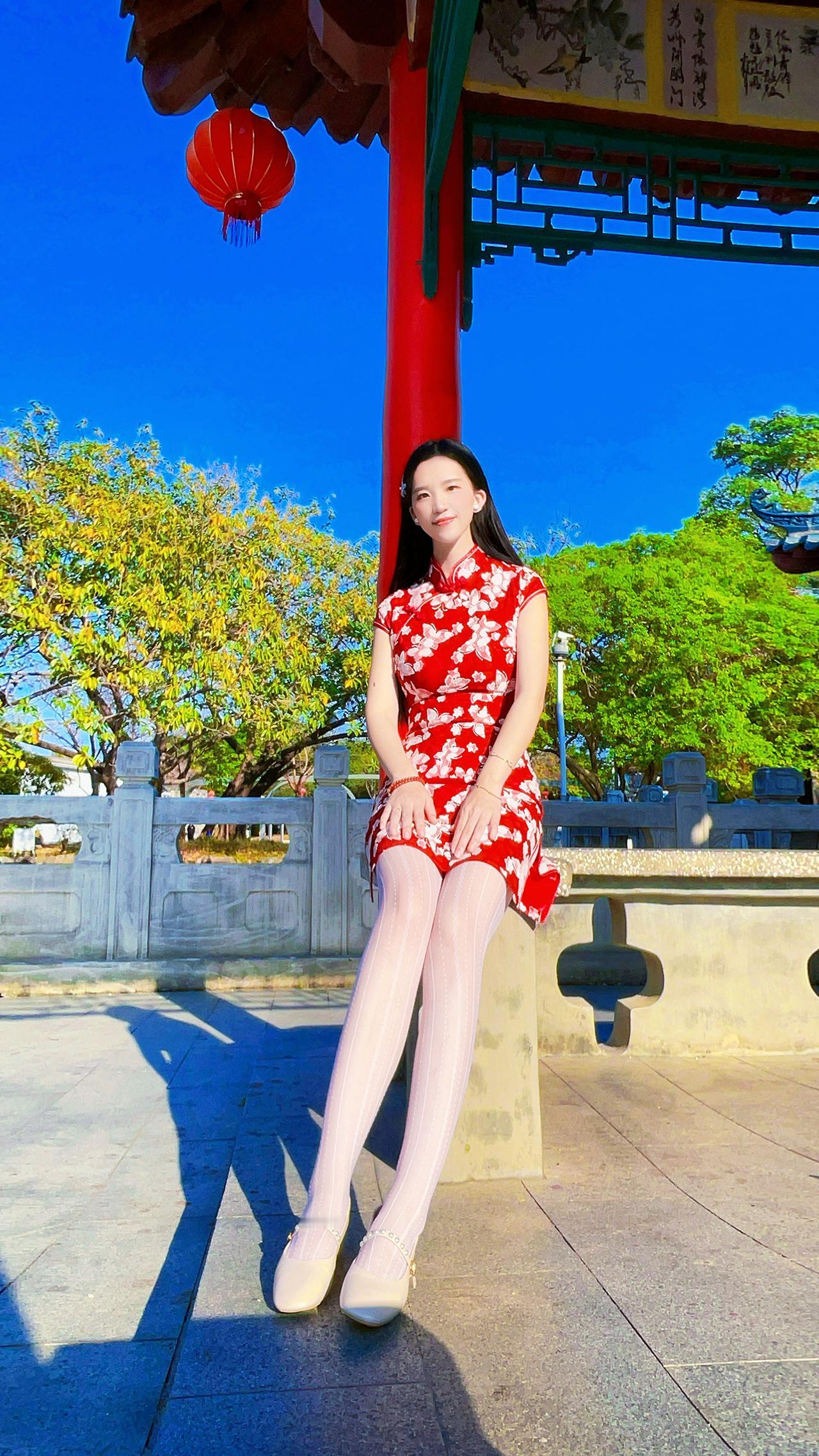 一袭碎花红旗袍，红底上点缀着细腻的花朵，仿佛将春日繁花穿在身上，既端庄典雅又透着