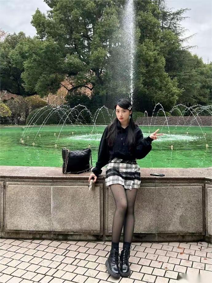 绿意盎然的公园里，少女与喷泉相伴，享受宁静时光。