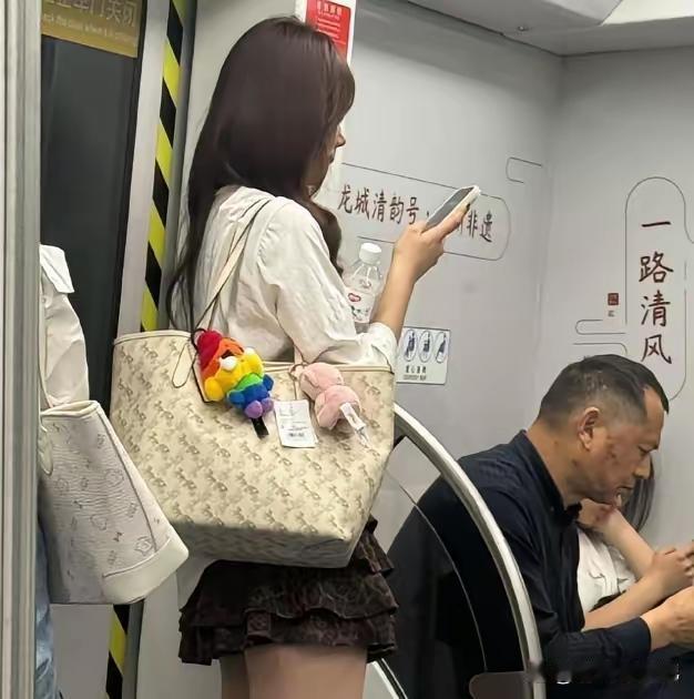 香肩挎名包，上班乘公交。无坐依门站，端庄手机瞧。