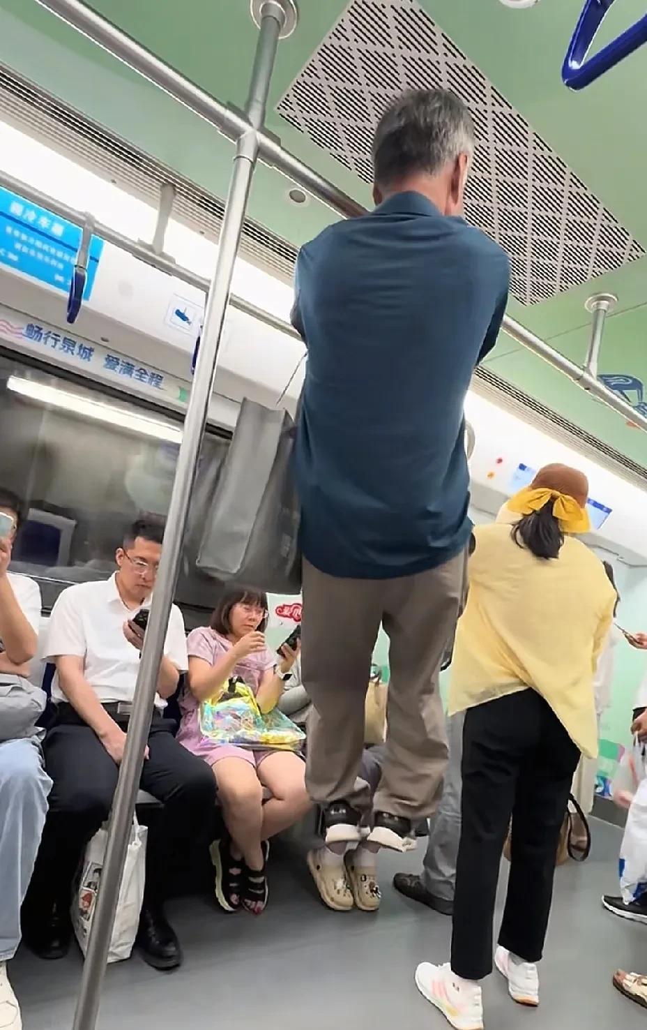 这是发生在济南地铁上的一幕，一名大爷在地铁的扶手杆上做起了引体向上，不得不说这大
