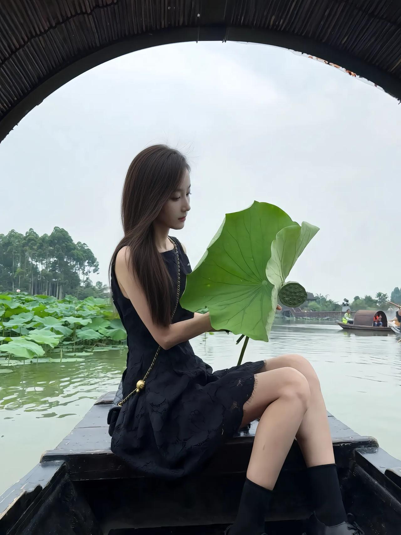 撑伞乘船游湖，黑裙飘飘，绿荷相伴，静享江南水乡的宁静与美好。