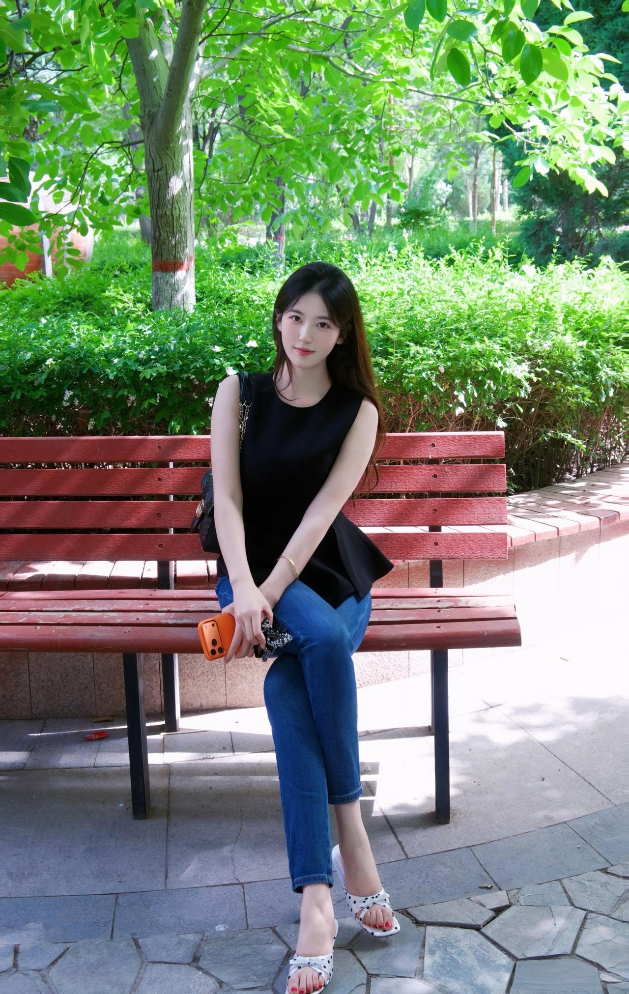 一个女孩坐在公园长椅上。