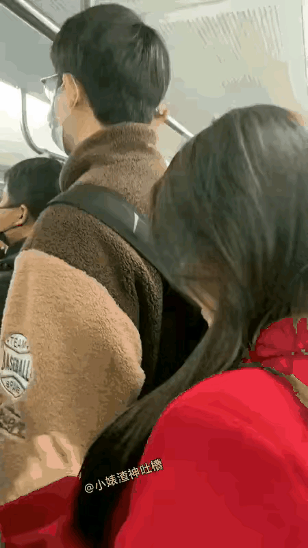 地铁里人特别多，一个穿红衣服的姑娘，一直盯着旁边的男生看。那男生穿棕色外套，看着