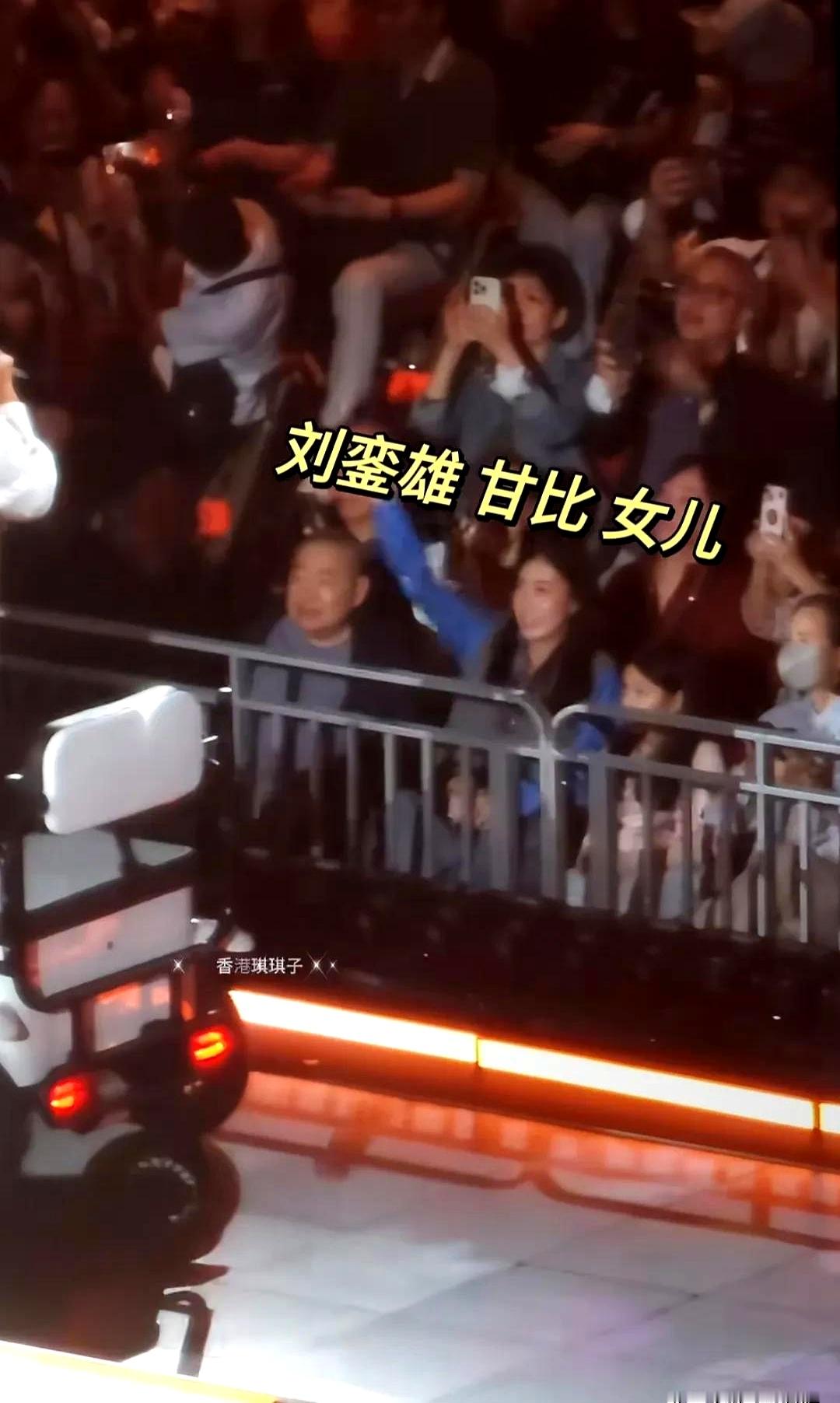 谭咏麟香港红馆演唱会现场，75岁富商刘銮雄带着老婆甘比和小女儿罕见现身，甘比坐在一旁挥手，身材发福的