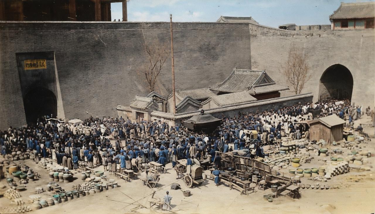 1907年，北京朝阳门瓮城。城门下挤满了赶市的百姓，地上堆成山的水缸瓦罐，是老