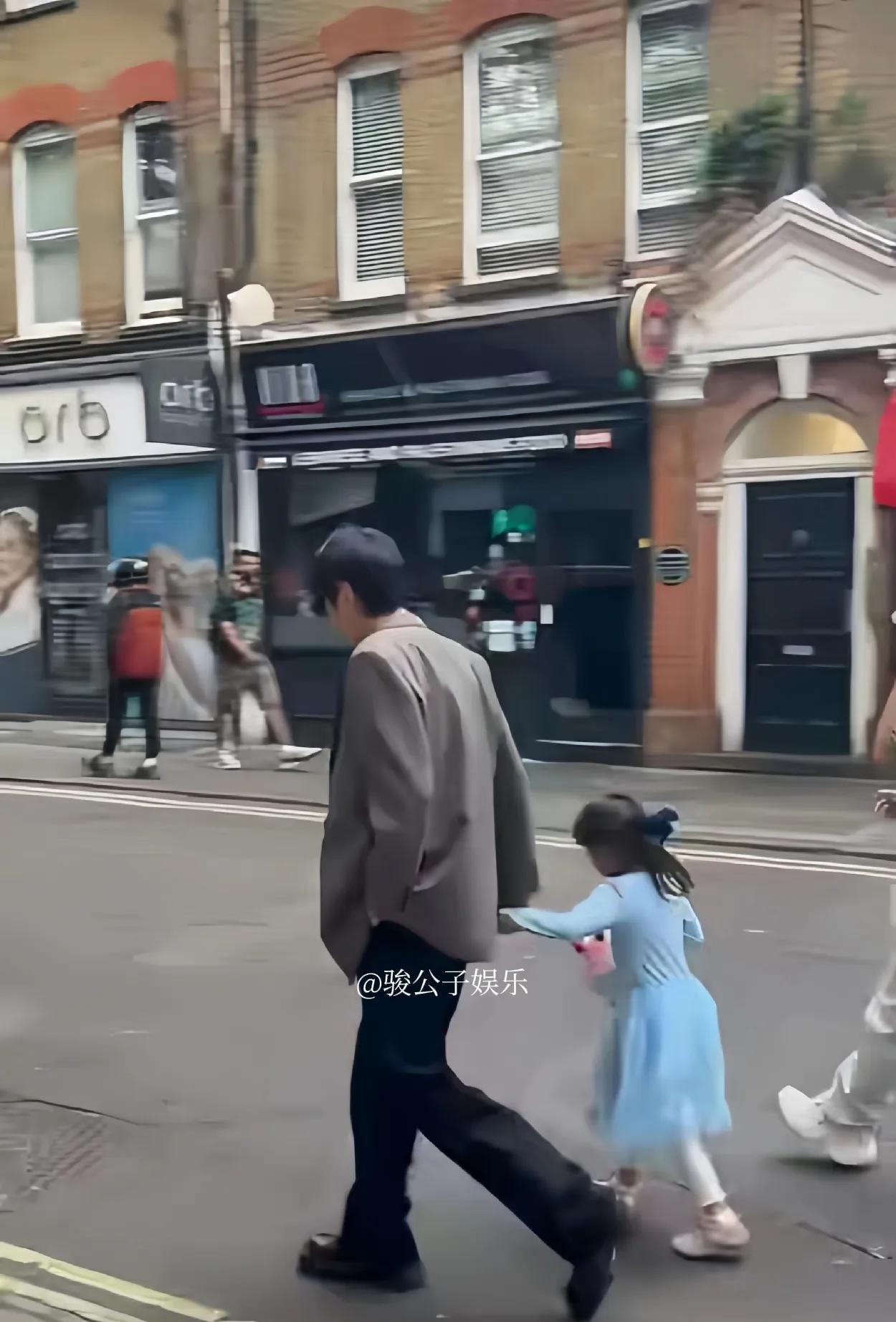 张若昀在伦敦被拍到带娃出行，父女俩手牵手一起走，他还亲切地搂着女儿的肩膀，画面十