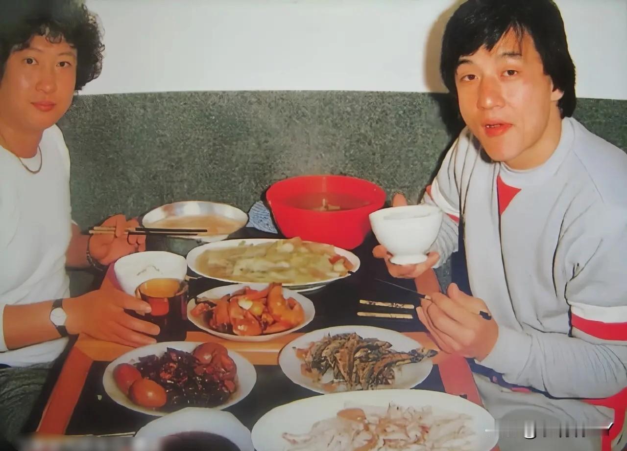 这是成龙与洪金宝拍戏间隙正在吃饭时的一张老照片，拍摄于上世纪80年代。那时候两人