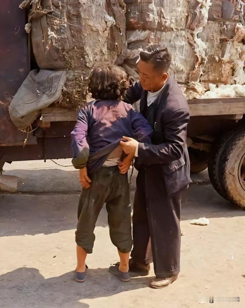 这是一张老照片，照片反映的内容是一个男子在搜身，必搜身的人是一个女子，旁边停着一