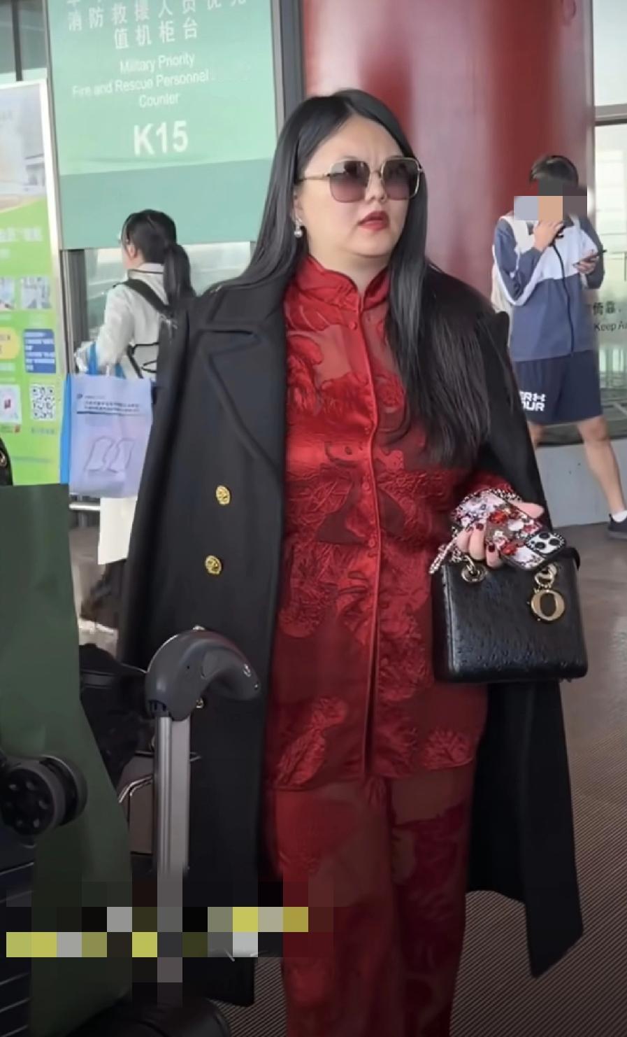 李湘的品味确实不一样，里面是深红色蕾丝套装，华丽高贵，外面搭配一件黑色大衣，