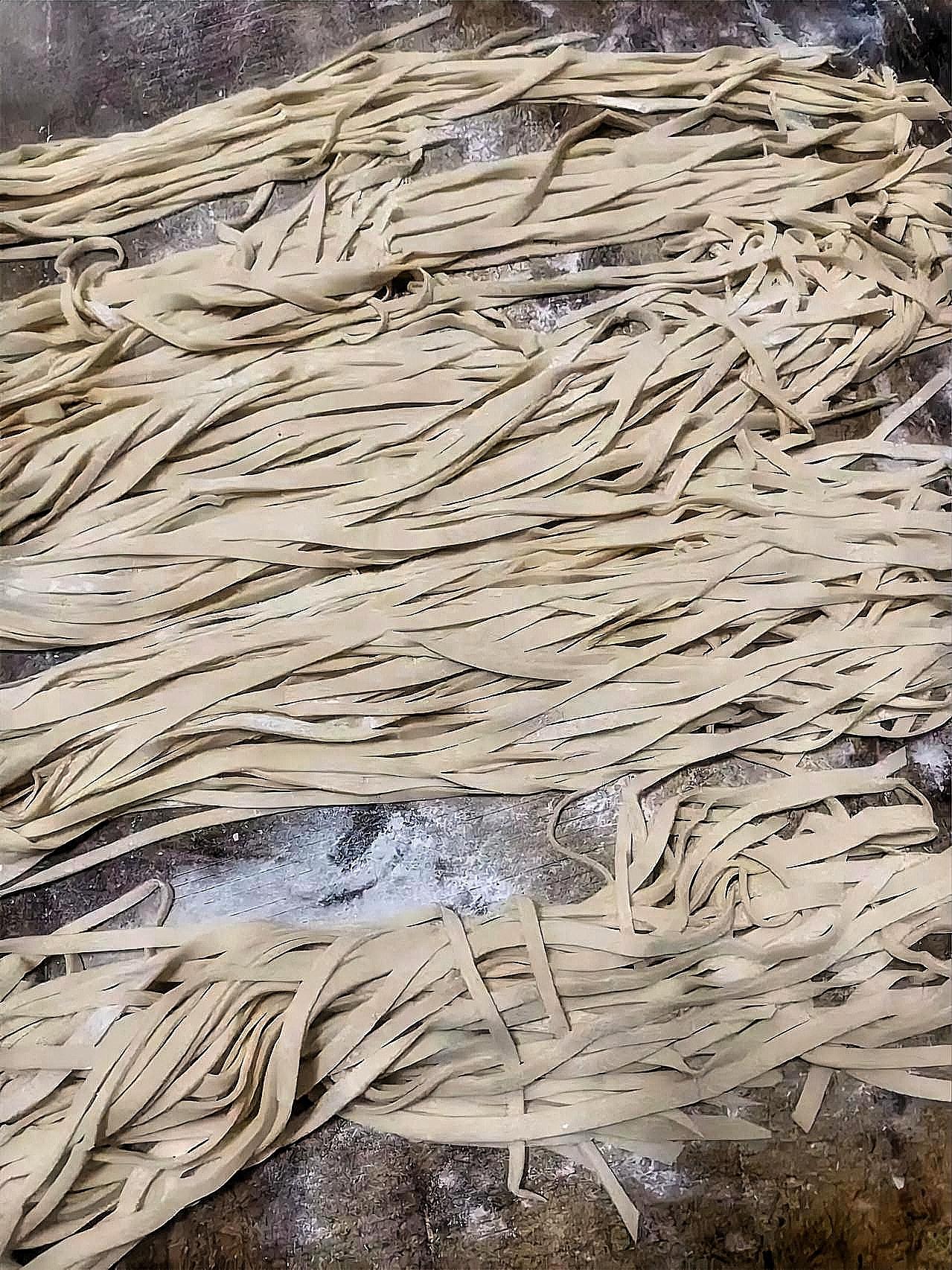 这手擀面条看着就实在，根根宽窄不一，带着面粉的糙感，透着一股子家常劲儿。没有机器
