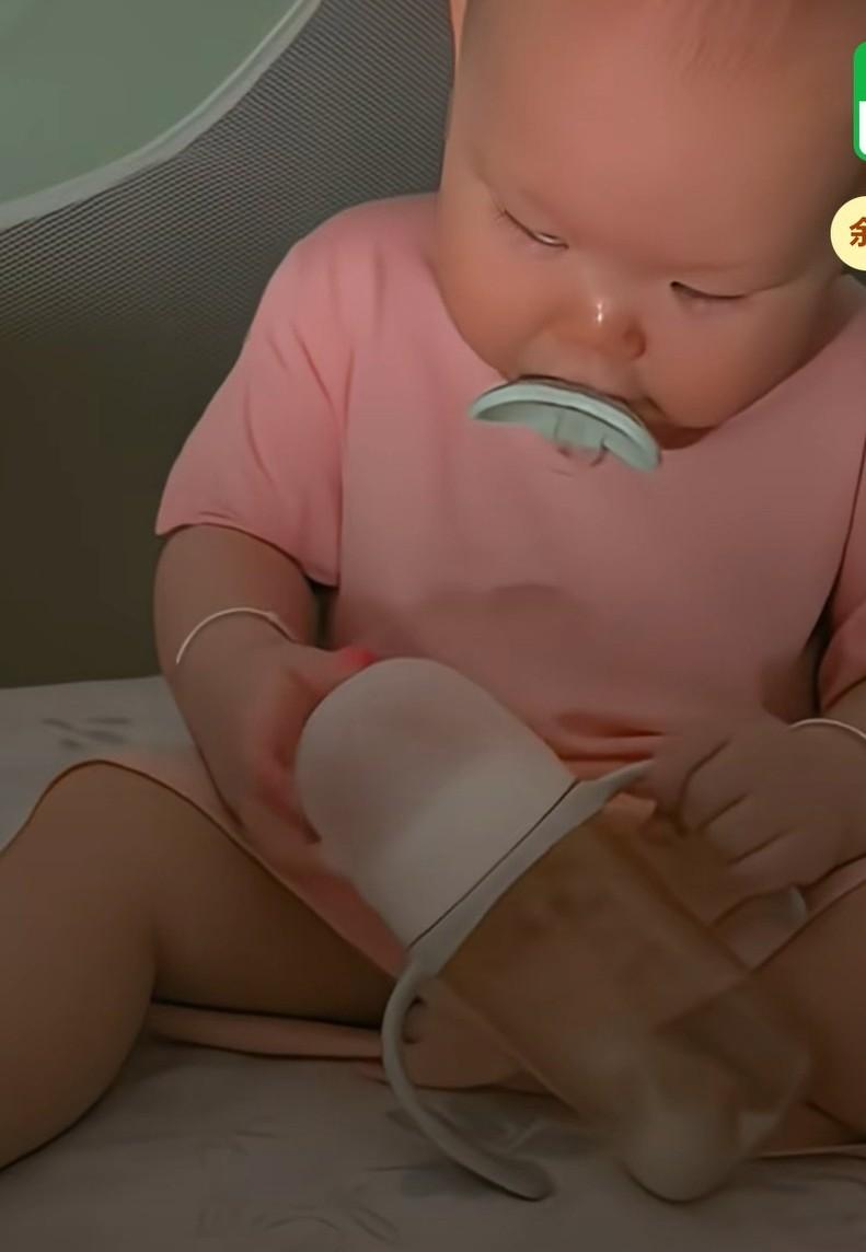 晚上宝宝喝完奶已经困的不行了，自己拿起安抚奶嘴叼在嘴里，然后拿起奶瓶盖就自己往