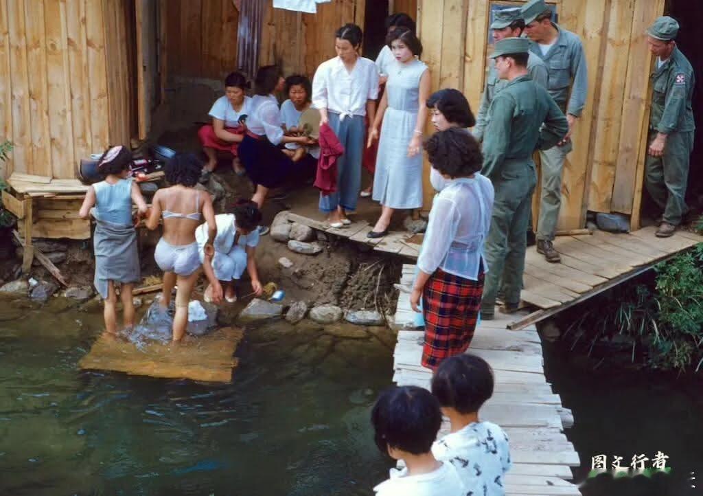 1959年，韩国釜山，驻韩美军附近的基地村内，几名美军大兵正在饶有兴趣的看着当地
