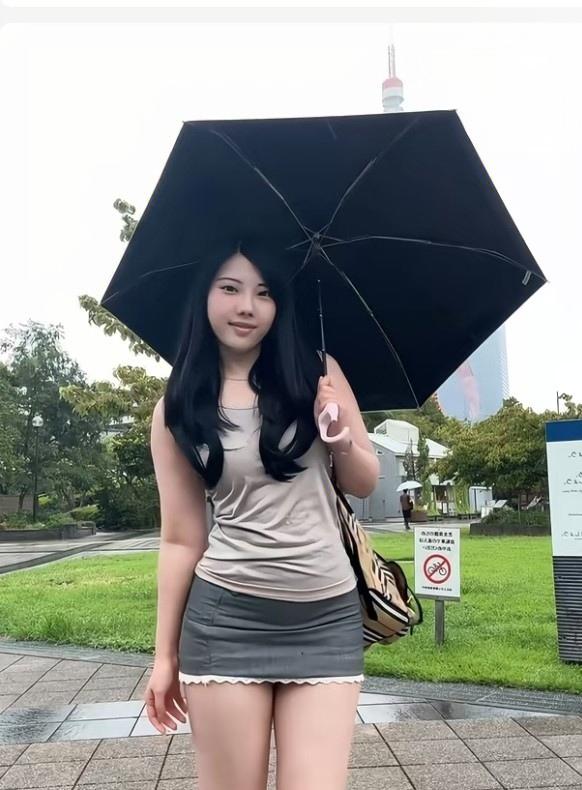女士打伞雨中漫步。