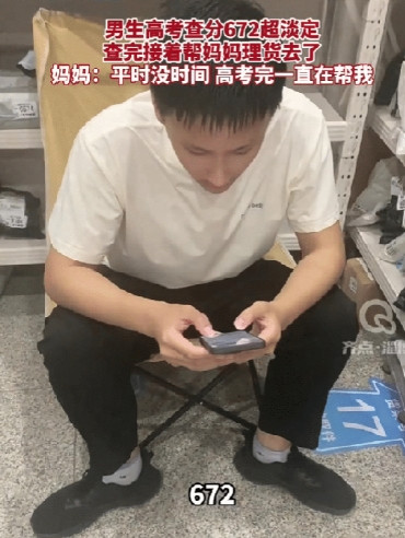 6月25日，山东淄博，男生在快递店帮助妈妈理货，到了可以查高考成绩的时候，他坐在