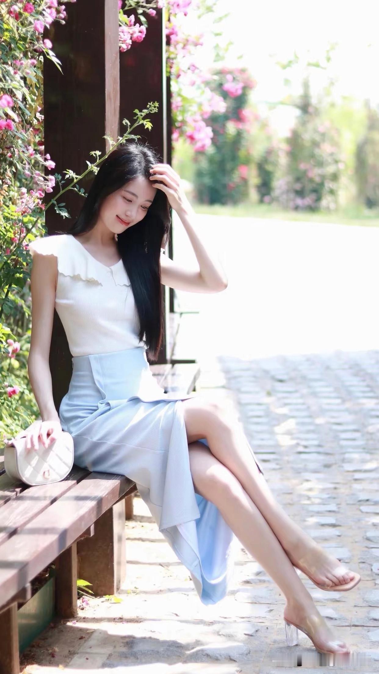 想象一下，在阳光正好的日子里，一位身着浅蓝裙摆的女子置身于花园中。那浅蓝的裙摆，