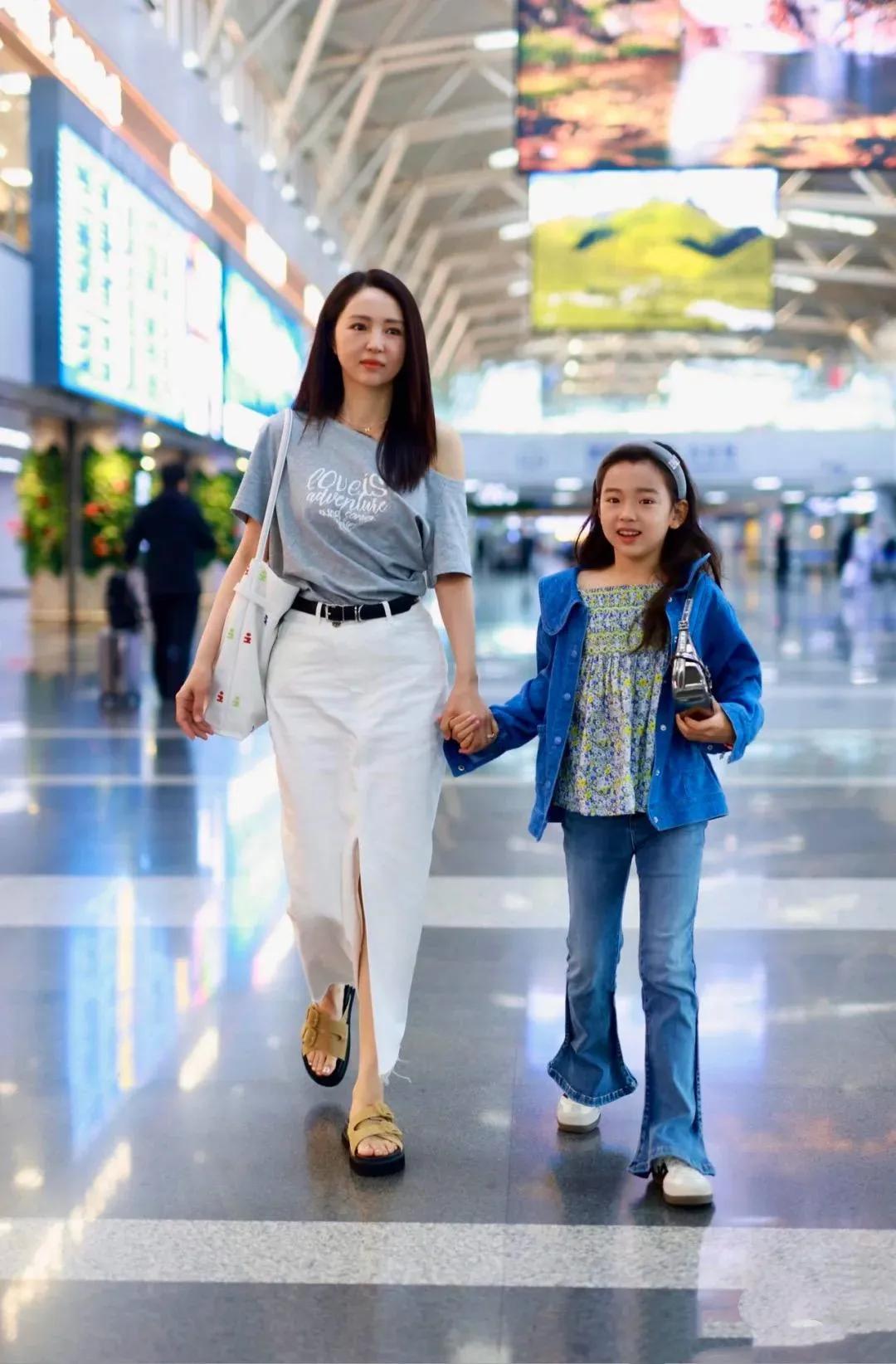 45岁董璇带女儿走机场！灰露肩衫配白裙温柔似水，小酒窝颜值太能打，这气质可以直接