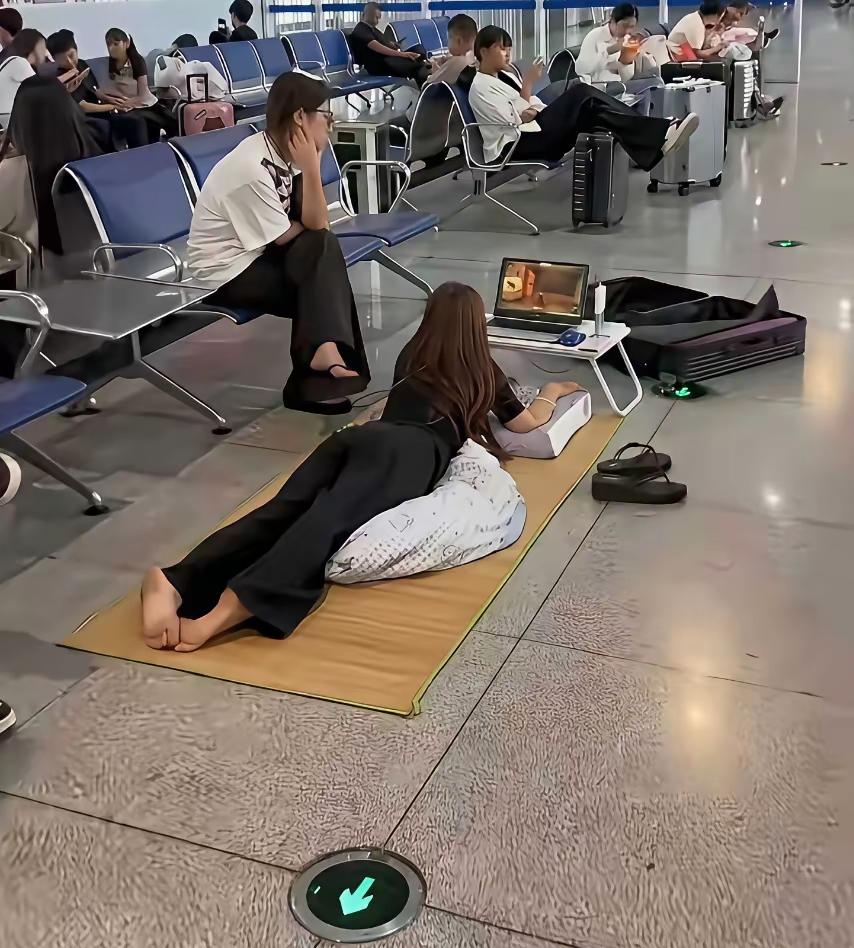 候车大厅里的一幕，看完之后真让人感慨万千。姑娘直接铺上凉席躺在地面，趴在垫子