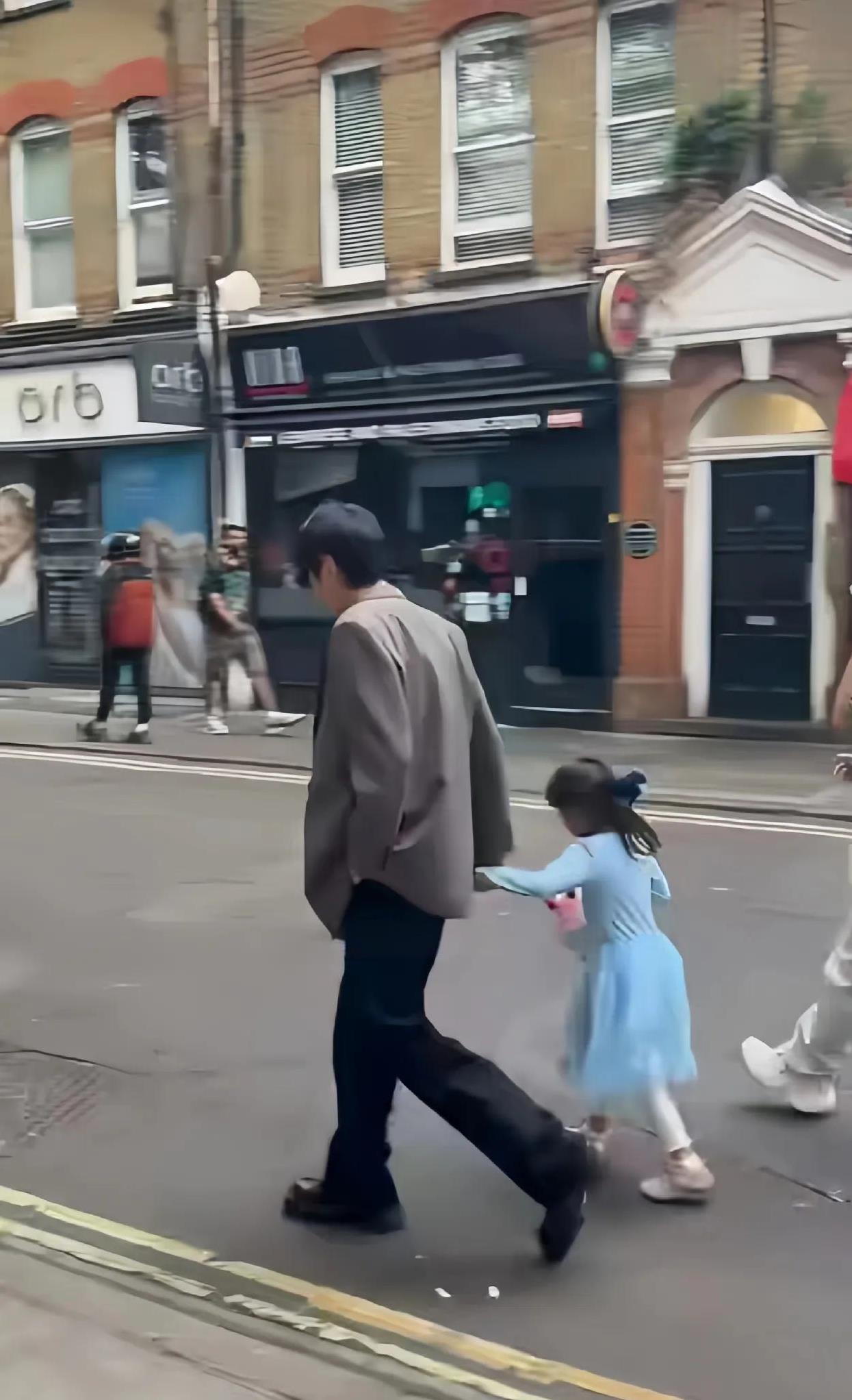 张若昀在伦敦被拍到带娃出行，父女俩手牵手一起走，他还亲切地搂着女儿的肩膀，画面十
