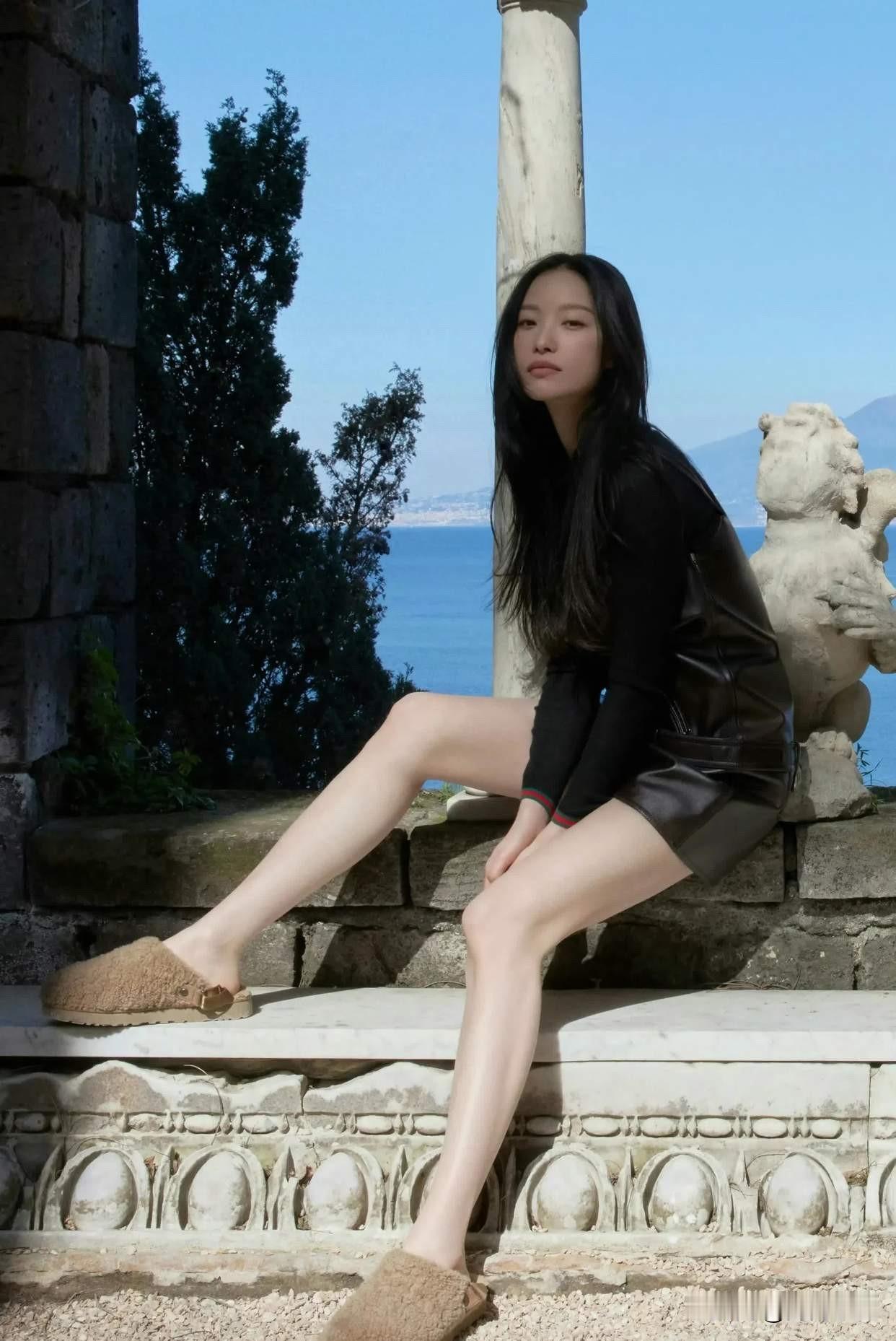 倪妮这组海边图好耐看！一身黑色皮质背带短裙，内搭修身黑色长袖，搭配毛茸茸的勃