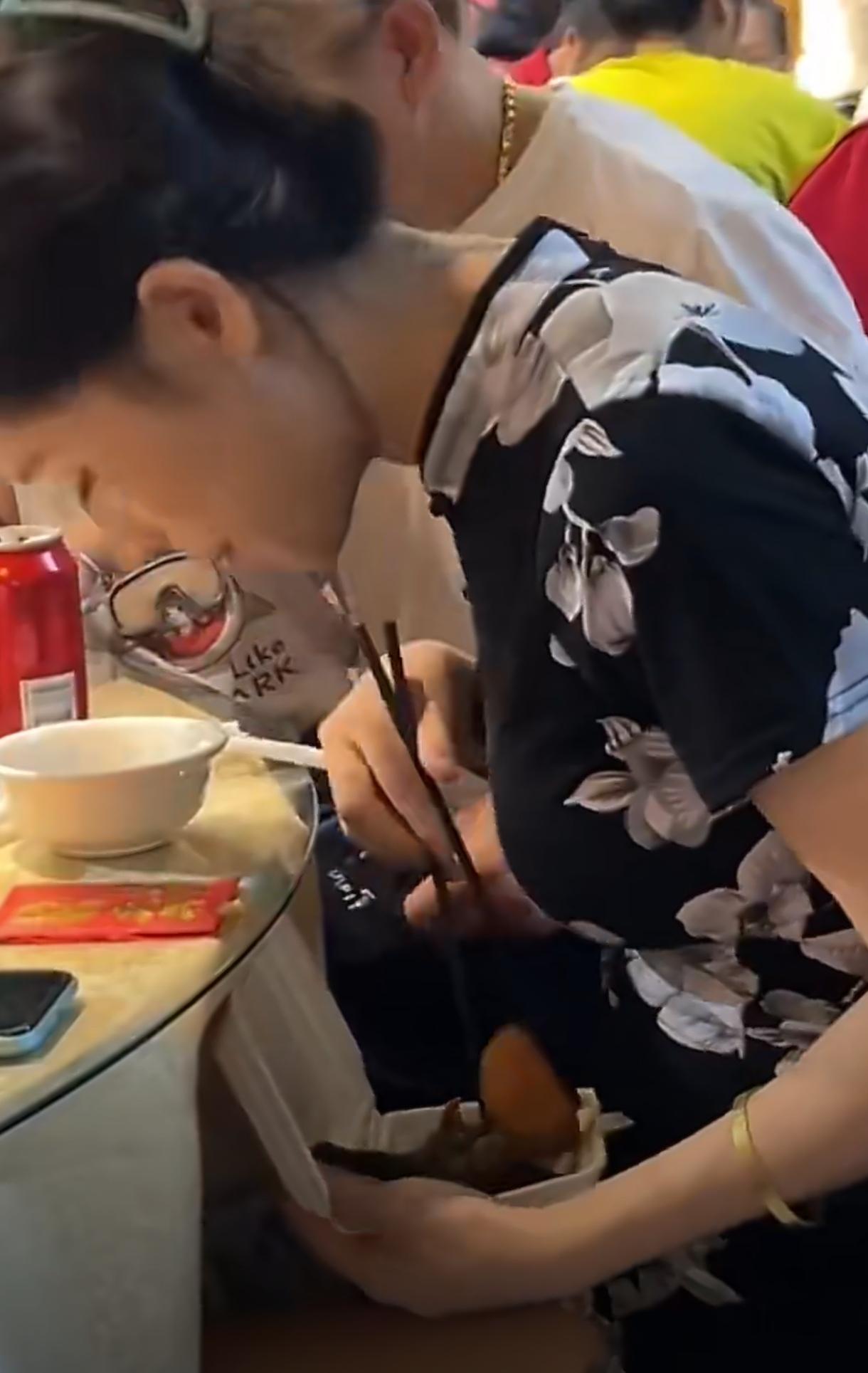 注意看这个旗袍美女，她在吃席的时候偷偷摸摸，她低头假装吃东西，实则是把夹的