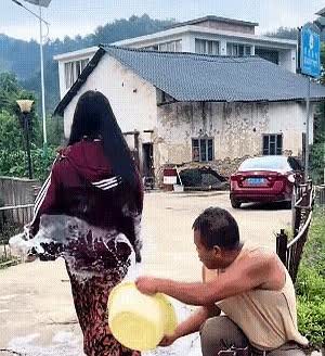 女子路过，男子故意向女子泼水！当即把女子惹怒了，女子拿起地上的砖头，刚想
