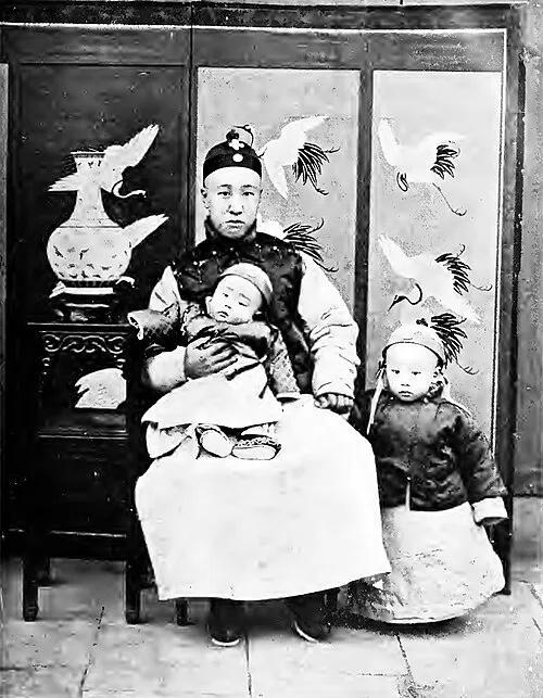 1908年，醇亲王载沣与3岁的长子溥仪和1岁的次子溥杰的合影，镜头中的溥仪穿着小