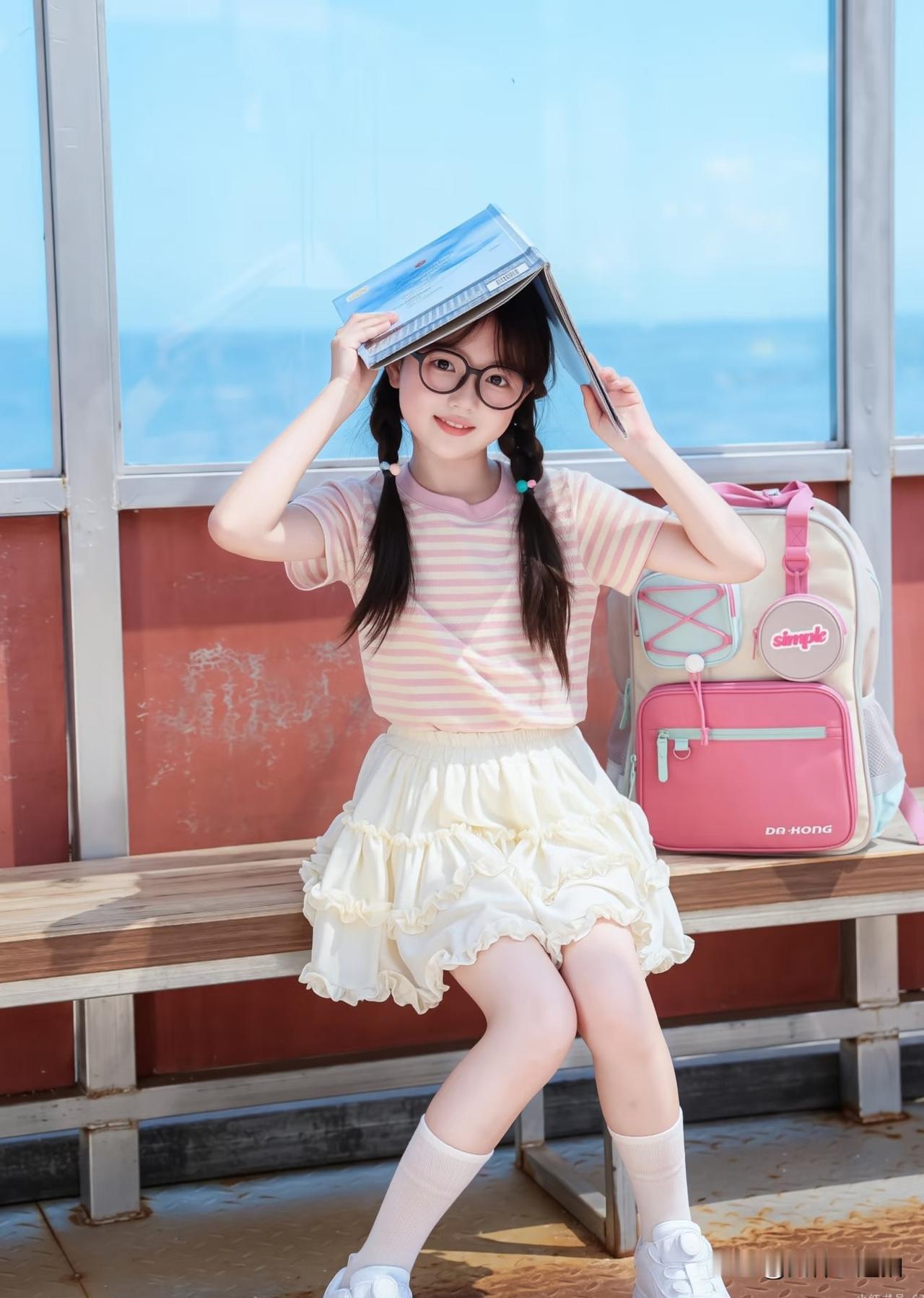 阳光明媚，小女生坐在长椅上，玩得很开心。