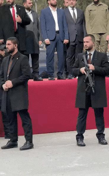 叙利亚一场寒酸的阅兵仪式。阅兵现场就设在一条马路上，几张桌子拼起来，上面铺上