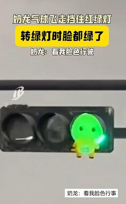 “看我脸色！”广西北海，一个小朋友脱手飞走的奶龙气球，刚好卡在红绿灯绿灯的位置。
