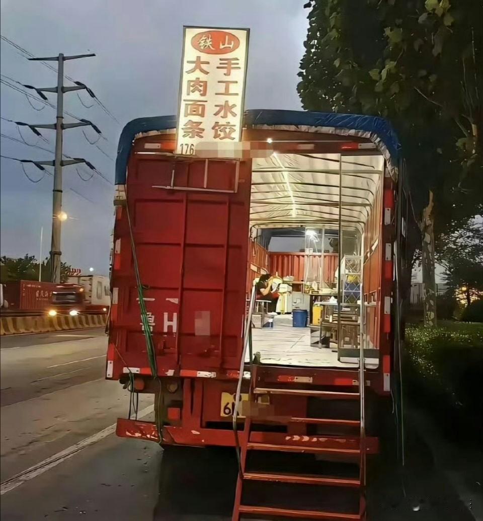 图片是网友拍摄的一位山东大叔的“货车水饺摊”。一辆红色大货车，后车厢一打开，桌椅
