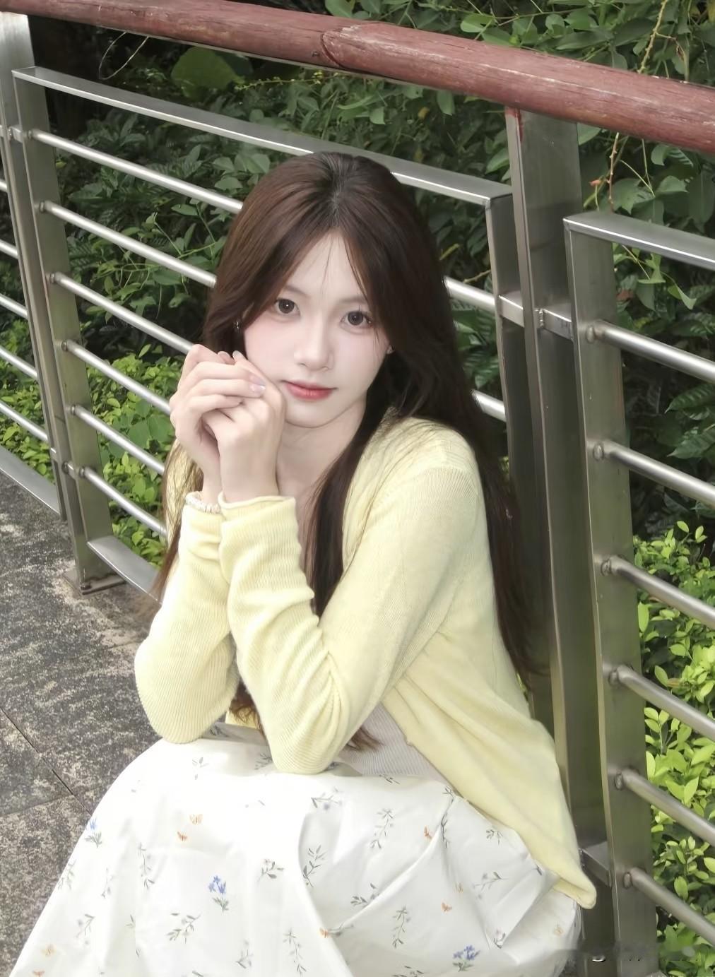 美女一个女孩坐在栏杆边，看着镜头微笑。