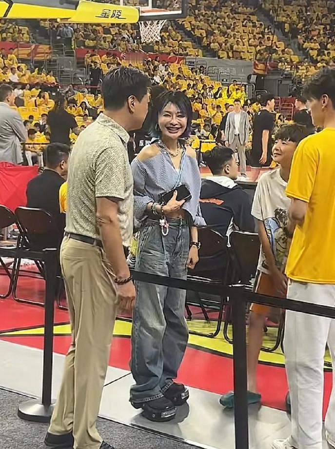 广东队老板娘领着儿子站在冠军旗前，指着最上面那几面对李春江说“这都是李指导带我们