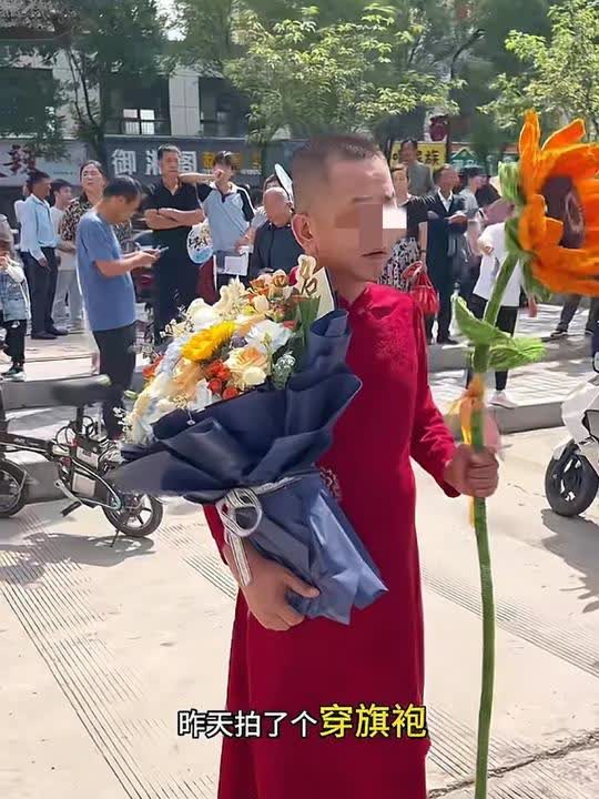陕西高考成绩揭晓已经好几天了，旬邑这位穿着裙子的举着向日葵加油的家长，在遭受着网