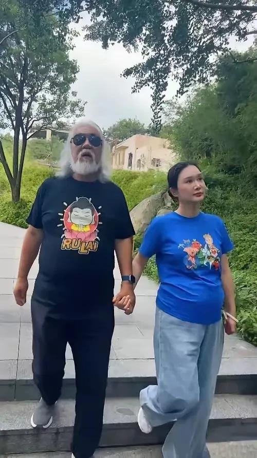 张纪中和杜星霖一起漫步在公园的石阶上，手牵手，享受着悠闲的时光，年龄差距太大爱情