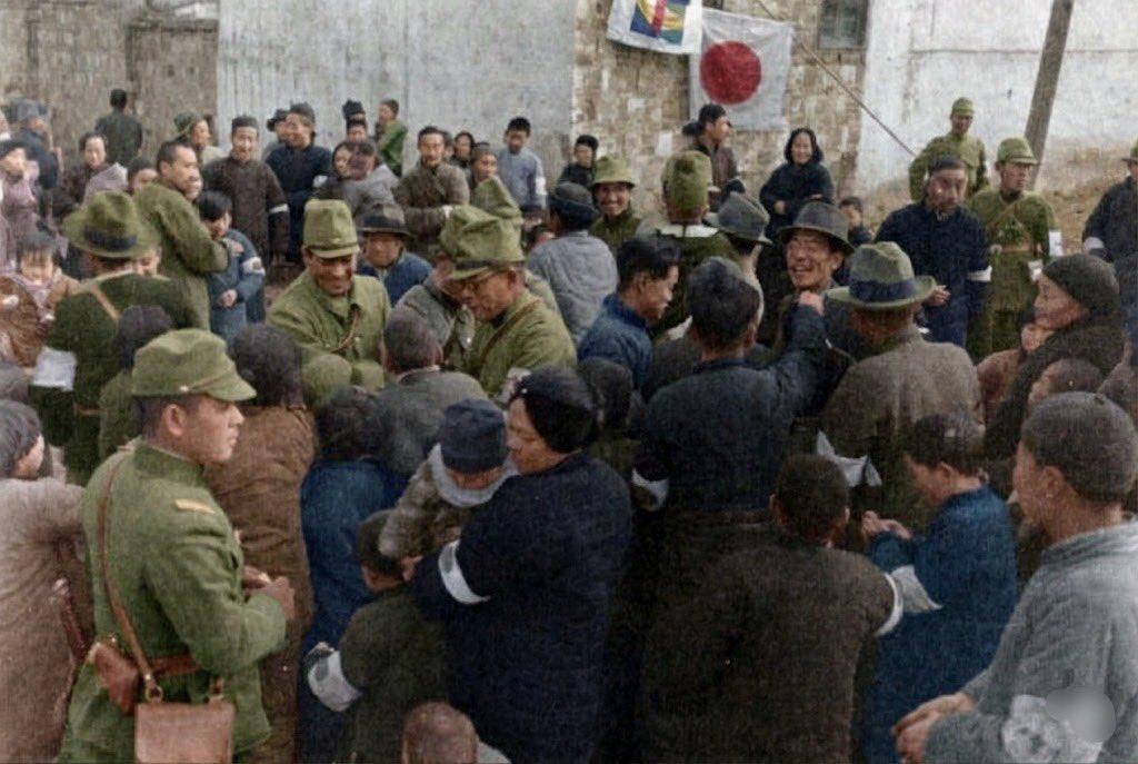 1937年12月的南京，照片中几十名中国平民（男女老少都有），伸出手、踮脚张望。