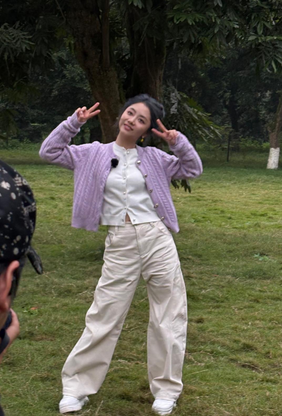 泸州一个公园的草坪撞见谭松韵，她正插着兜拍照，浅紫绞花毛衣软乎乎裹着，米白阔腿裤