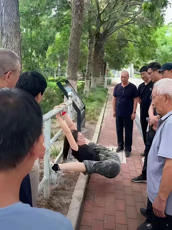 早上黑衣美女在公园健身吸引一群大爷围观只见美女双臂抓杆腰部一发力整个