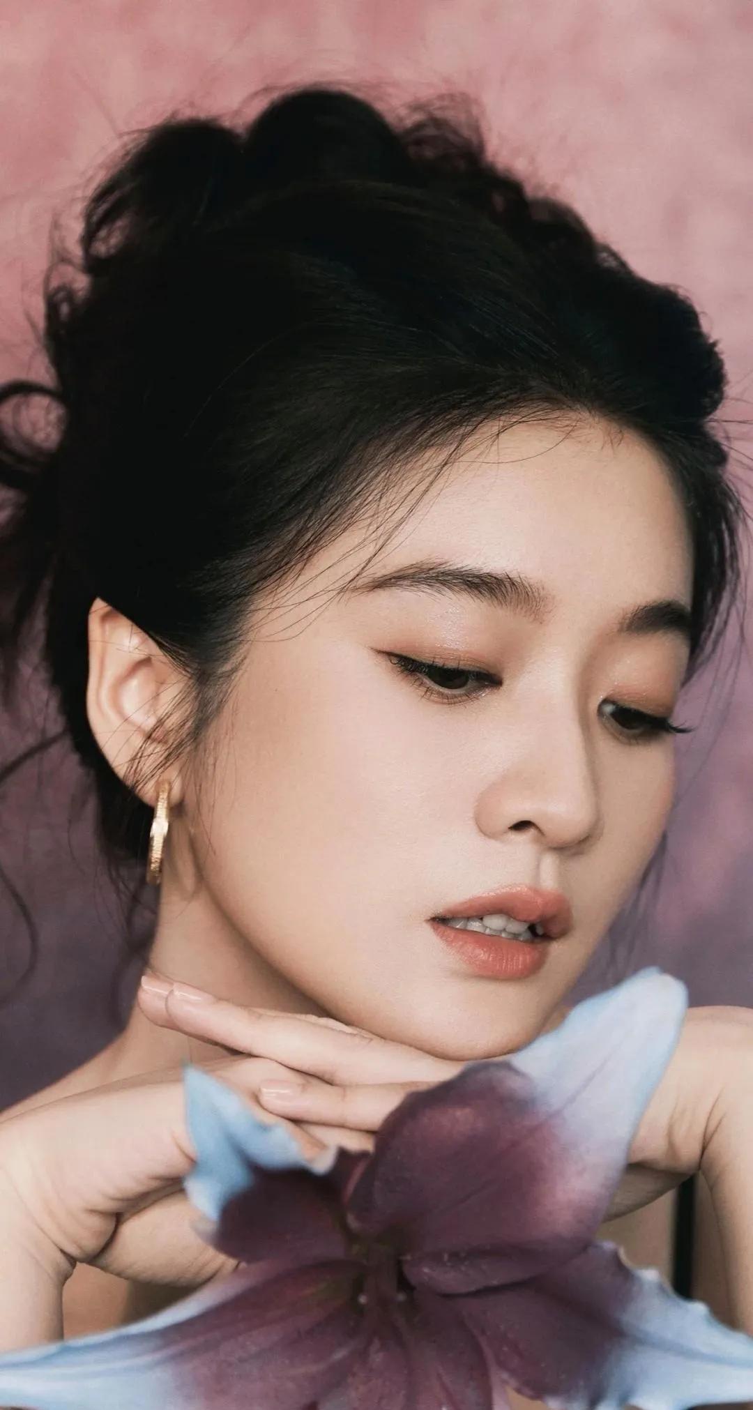 画面中的张雪宛如落入人间的精灵。她身着简约的裙装，在柔和自然光线下，每一个角度都