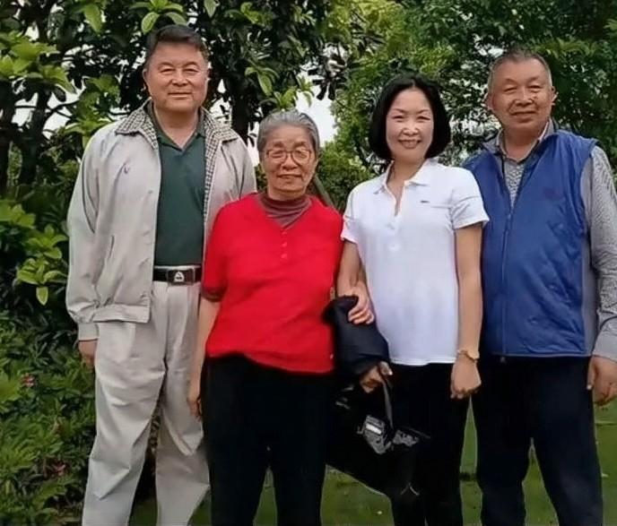 这张户外合影拍摄于绿树葱茏的庭院，草木繁茂，绿意盎然。画面之中，粟裕大将的家人齐