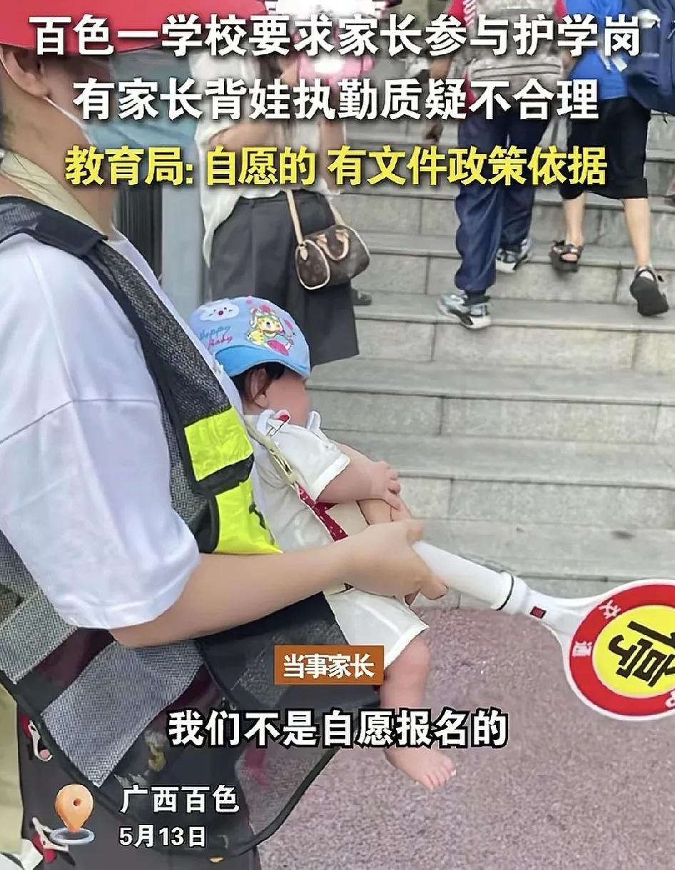 5月13日，广西百色一所小学一家长背着几个月大的小孩站护学岗。被质疑不合理，这位