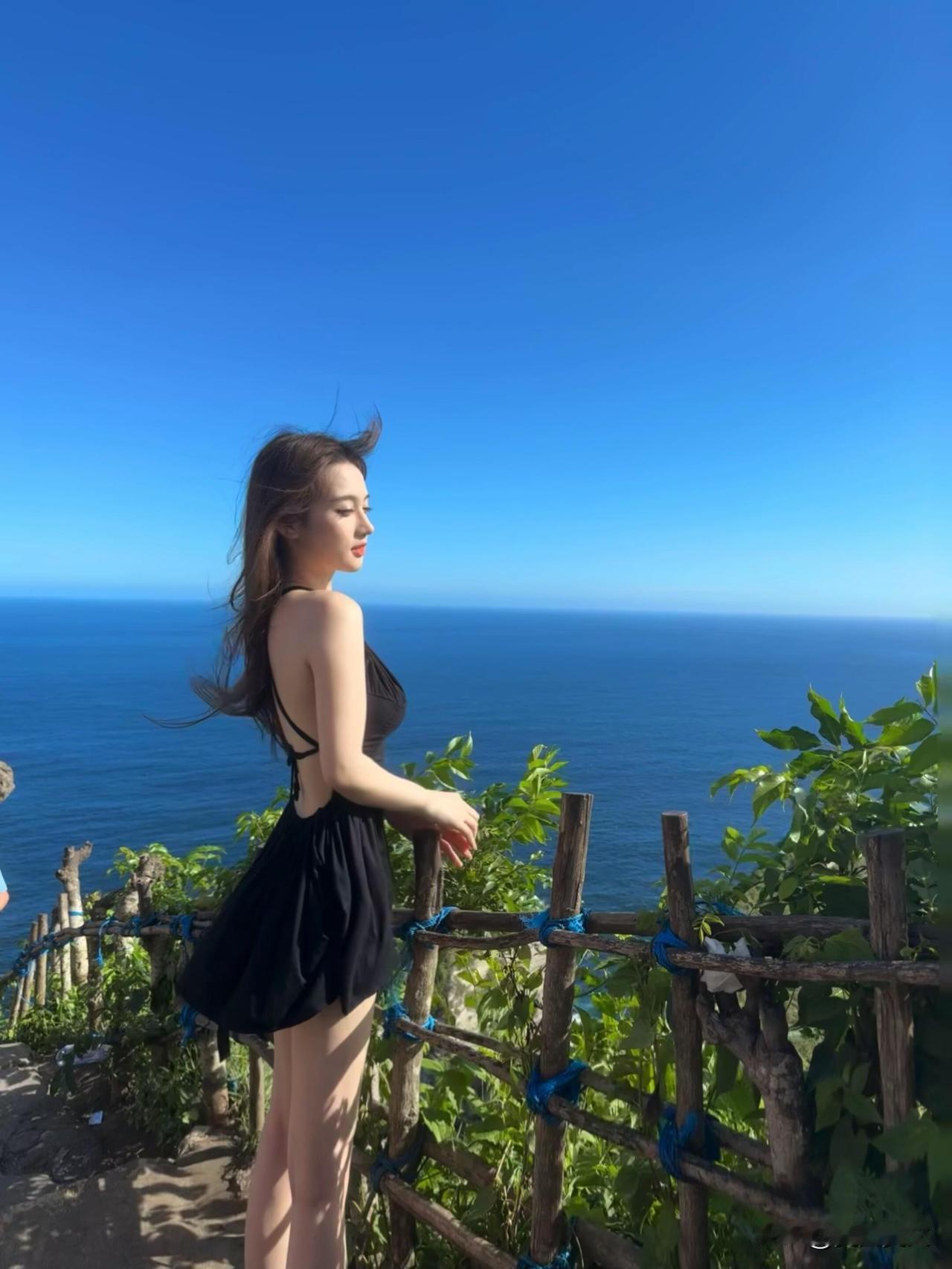 海边微风轻拂，黑裙飘逸，享受海天一色的宁静时光。