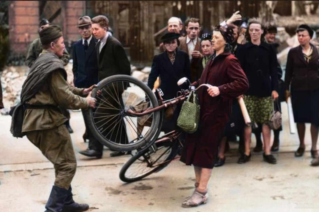 这张照片是1945年一名苏联士兵在德国柏林当街调戏德国妇女的场景。当时的大规模