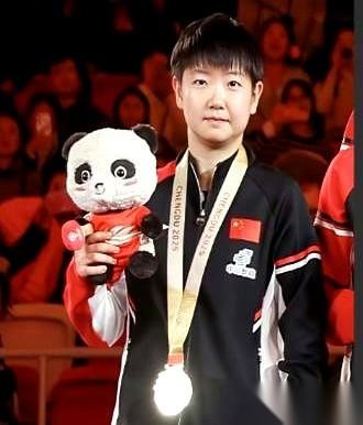 就挺魔幻的。领导让她低调点，往边上站，别太突出。结果呢？全场就她那块金牌，闪