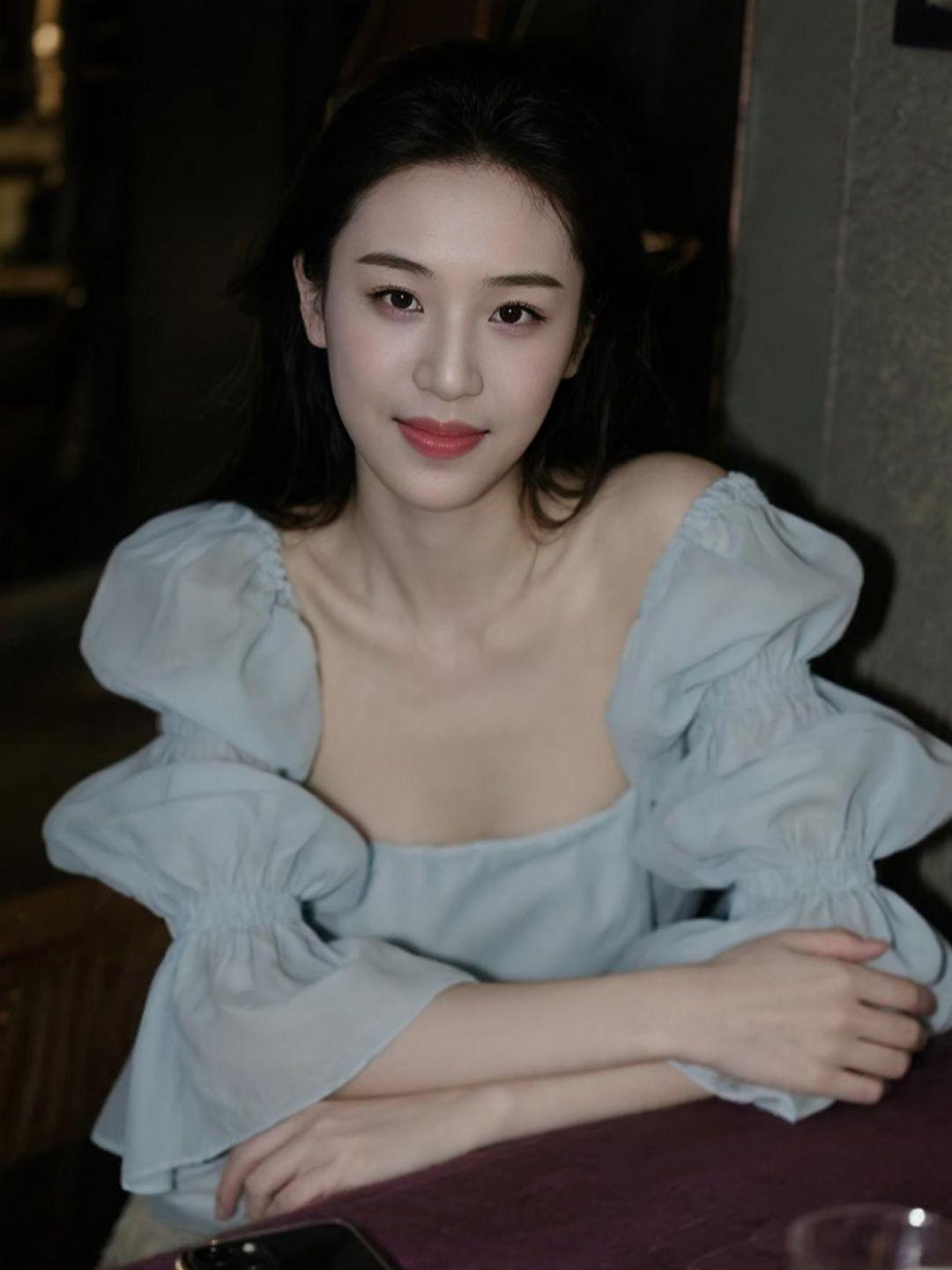 浅蓝色的连衣裙如同清晨的薄雾，轻柔地笼罩在身上，散发出一种宁静而优雅的气质。低饱